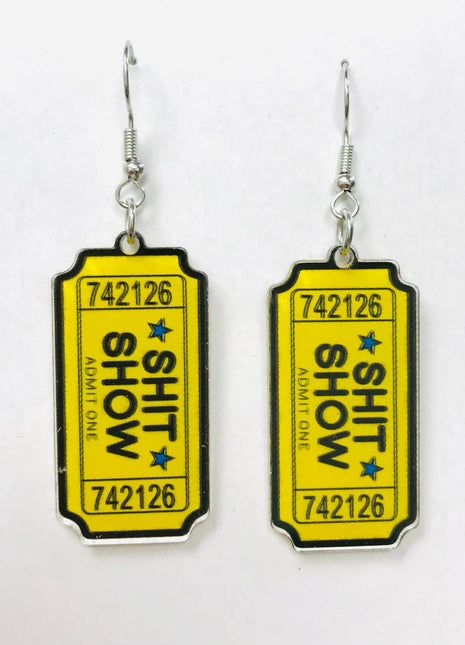 Acrylic earrings shaped like yellow admission tickets with "SHIT SHOW" text and blue stars.